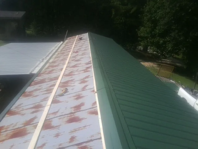 Old rusted panels beside newly installed green metal roofing — Wind Damage Roof Repair by Roofing Brothers in Pacolet Mills