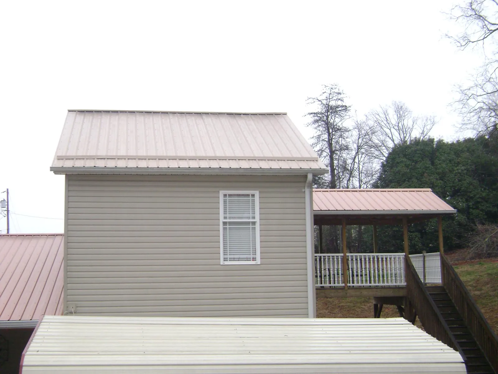 Tan metal roofs on a two story addition and attached porch, from a Roof Replacement job in Pacolet Mills