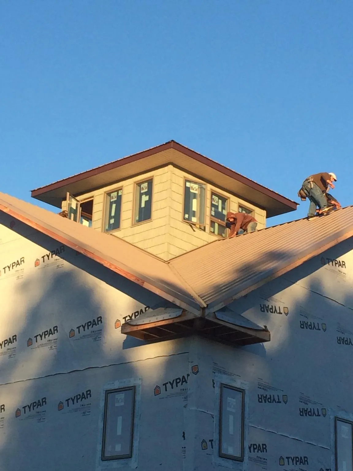 Roofers working around a rooftop cupola on a new metal roof at sunset — Roof Waterproofing in Pacolet Mills by Roofing Brothers
